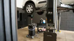 Van raised on a two-post ramp above an oil drainer during a service in the Pro Tuning workshop in Bournemouth.