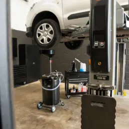 Van raised on a two-post ramp above an oil drainer during a service in the Pro Tuning workshop in Bournemouth.